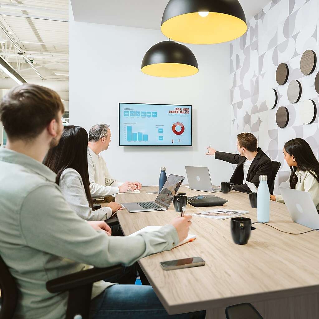 Meeting room with a wooden conference table and people presenting charts
