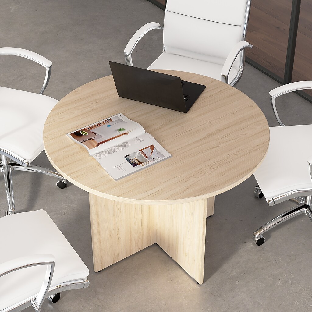 Round conference table with laptop and magazine, surrounded by white chairs