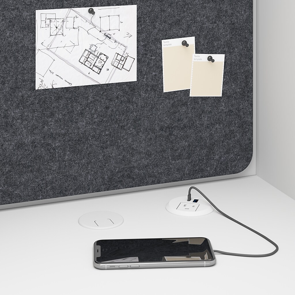 Grey fabric tackboard with papers pinned and a charging phone on desk