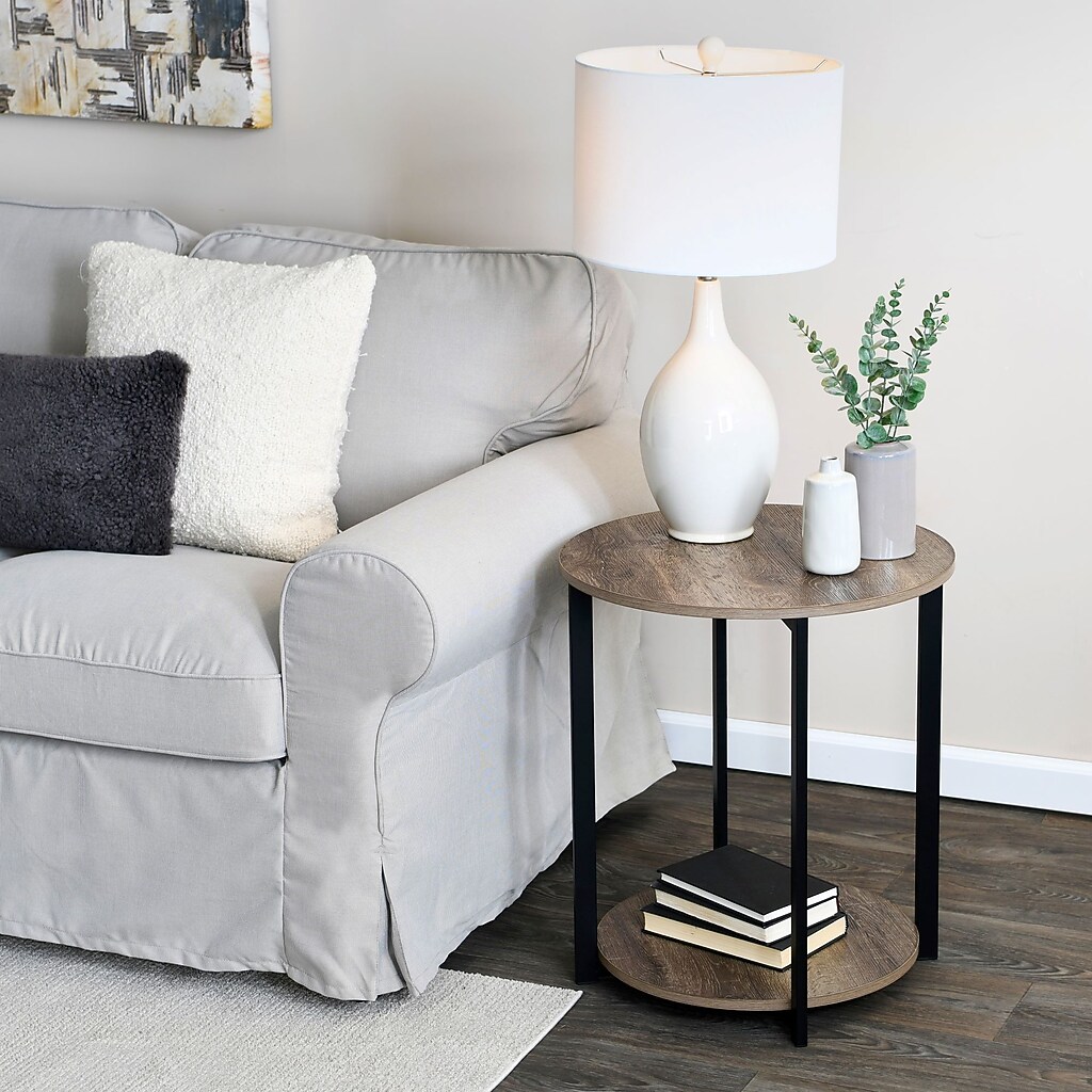 Round end table beside a sofa with lamp and decor