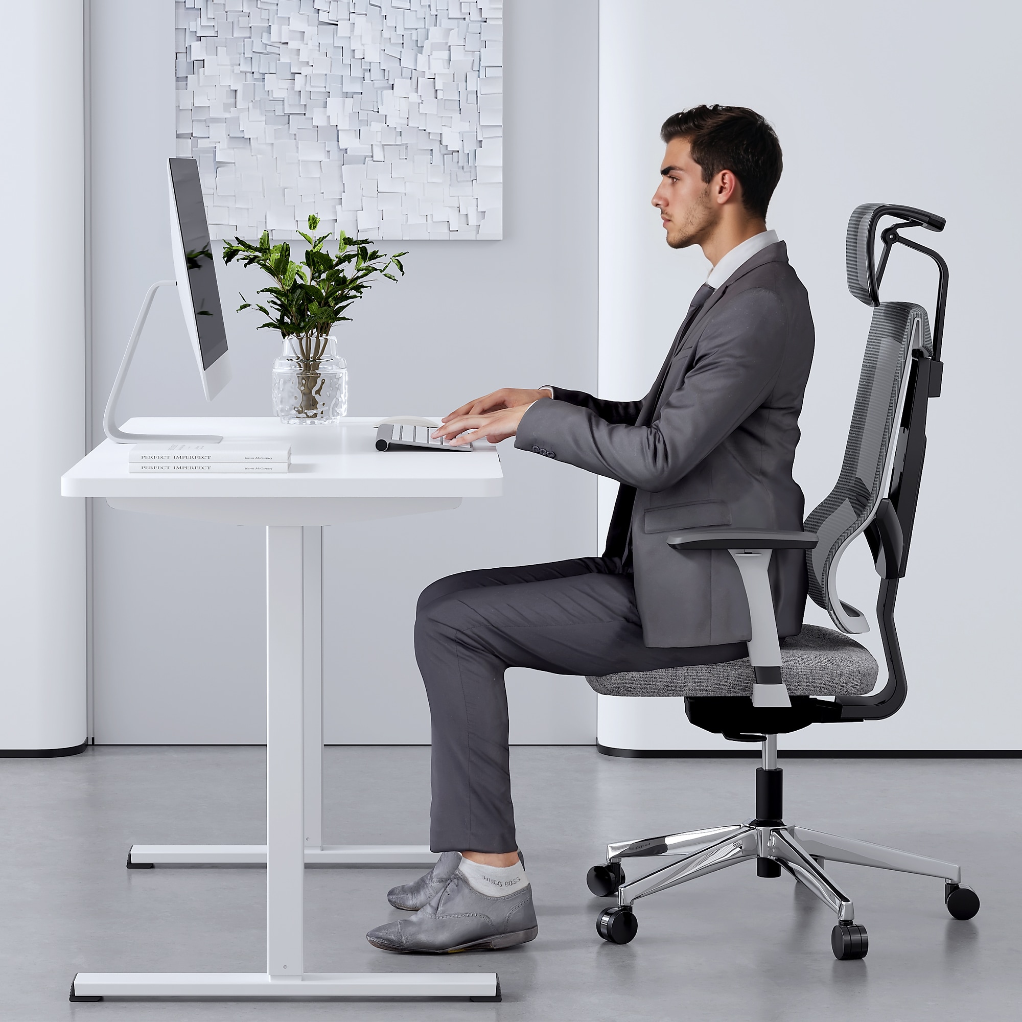 White electric adjustable standing desk in use with person working while seated