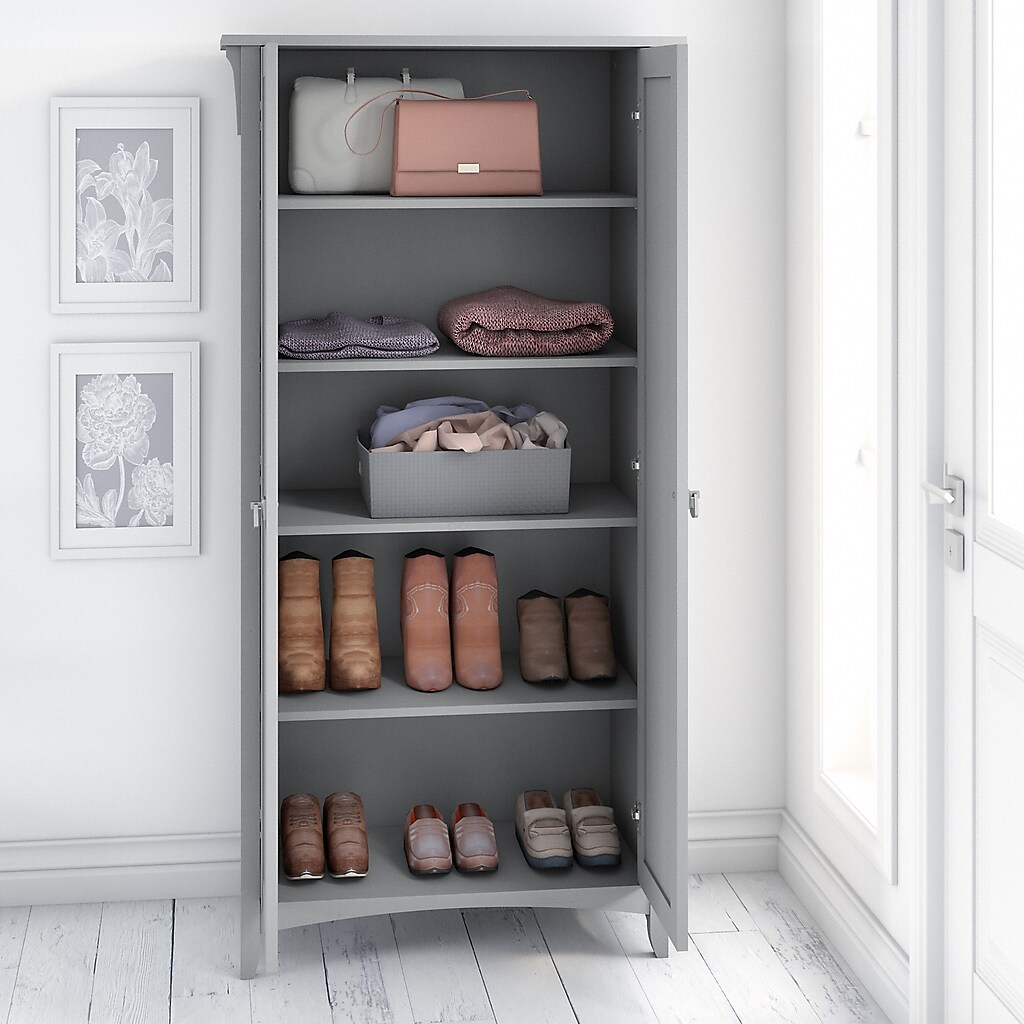 Open cabinet with multiple shelves containing bags, clothes, and shoes