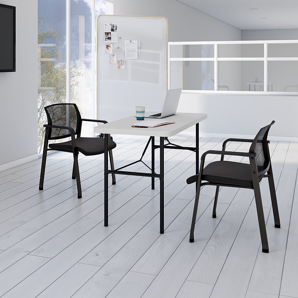 Two black chairs flanking a white folding table in a bright office